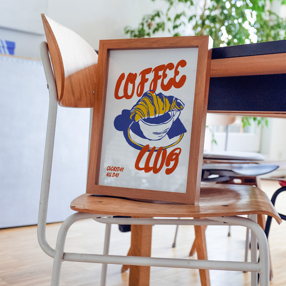 Coffee Club croissant print in a walnut frame on a bentwood chair