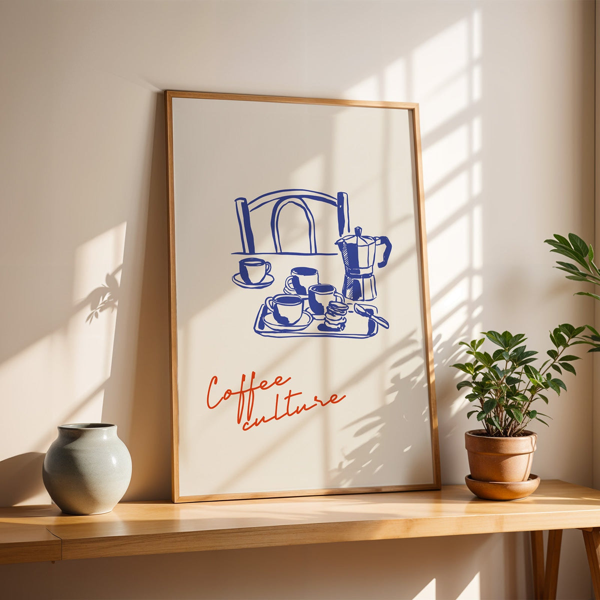 Coffee Culture poster in a slim oak frame on a sunlit wood console with a stoneware vase