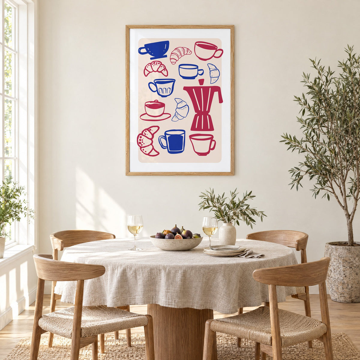 Moka pot, cups and croissants pattern in an oak frame above a round linen-covered dining table with figs and wine