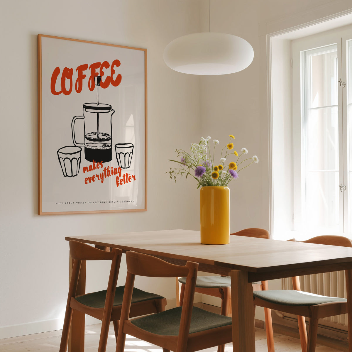 Coffee French press print in a slim oak frame above a dining table