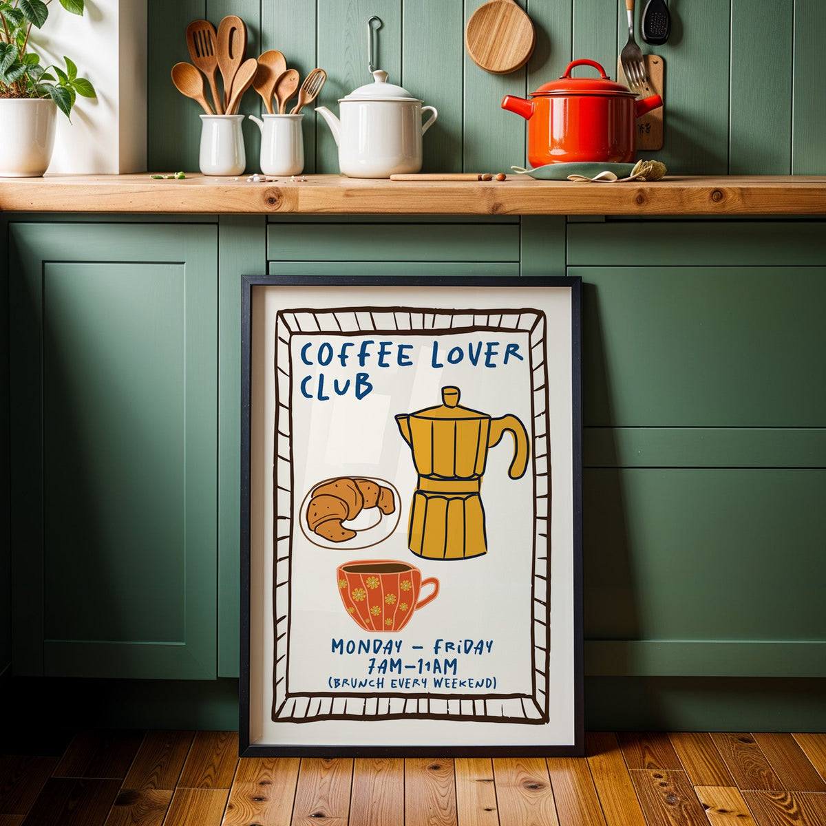 Coffee lover club moka pot print in a black frame against sage green kitchen cabinets
