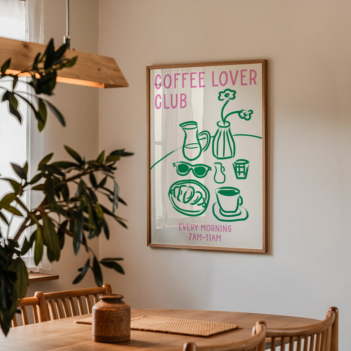 Coffee lover club morning print in a walnut frame above a dining table beside an olive tree