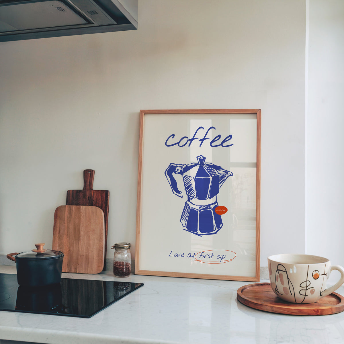 Blue moka pot print in a light pine frame leaning on a marble kitchen counter