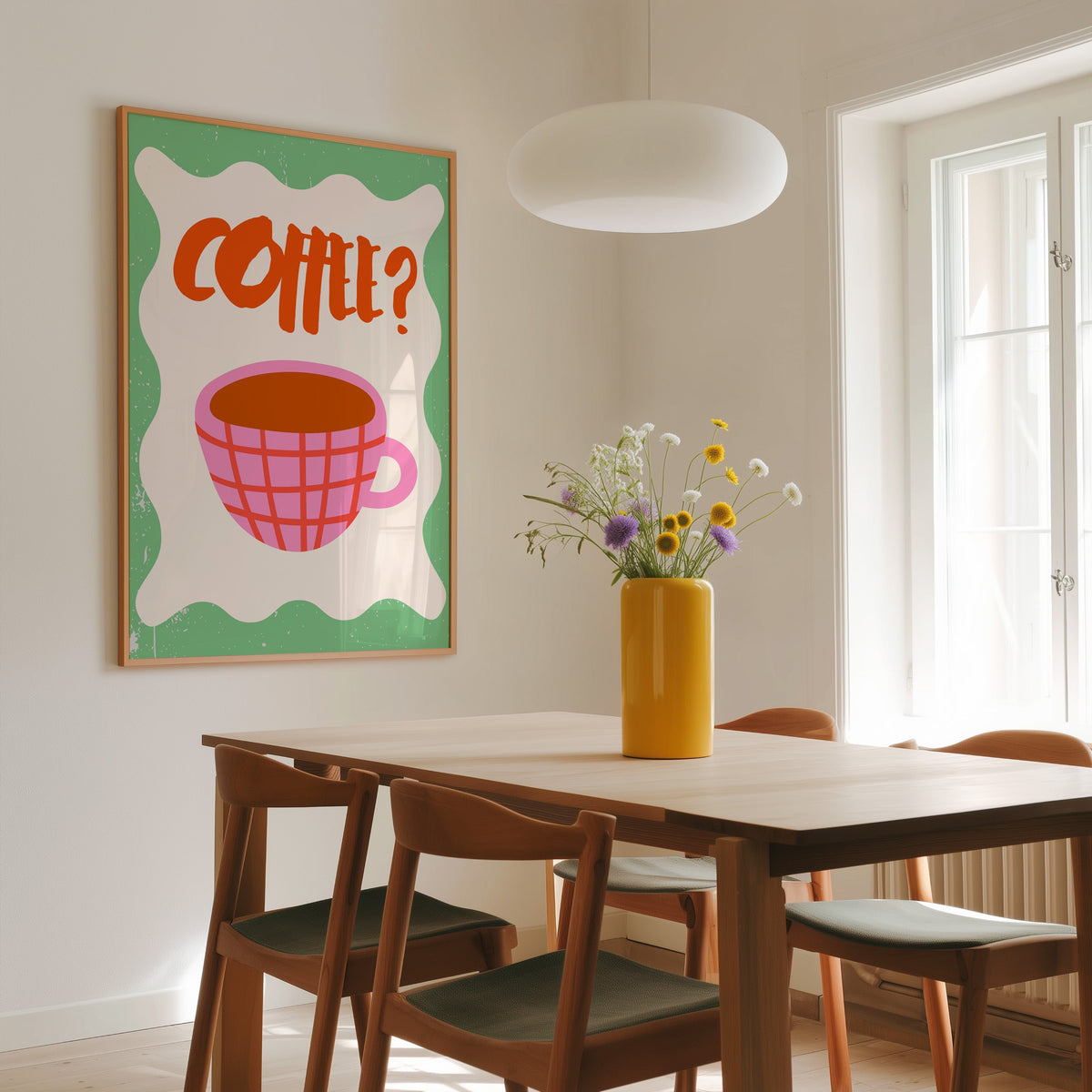 Pink check coffee cup print in a slim oak frame above a wooden dining table under a round pendant light