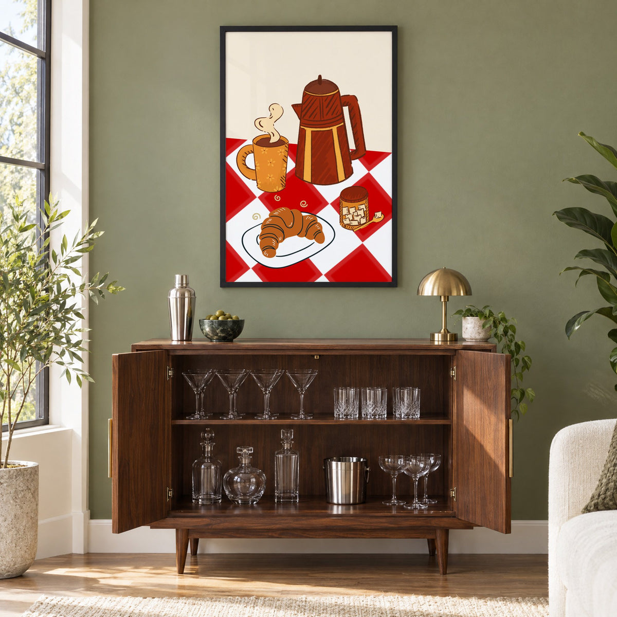 Coffee pot croissant red gingham print in a black frame on an olive green wall above a walnut bar cabinet with glassware