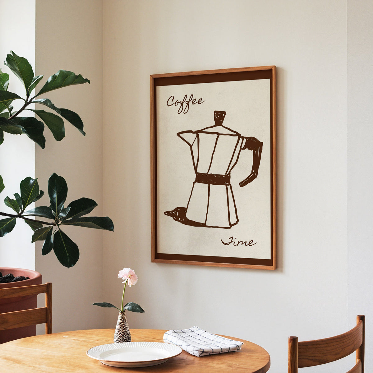 Coffee Time moka pot print in a walnut frame above a round table beside a fiddle-leaf fig