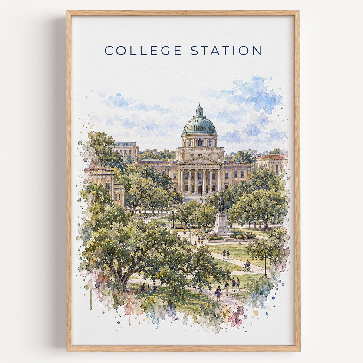 College Station watercolor print in a light oak frame on a plain white wall