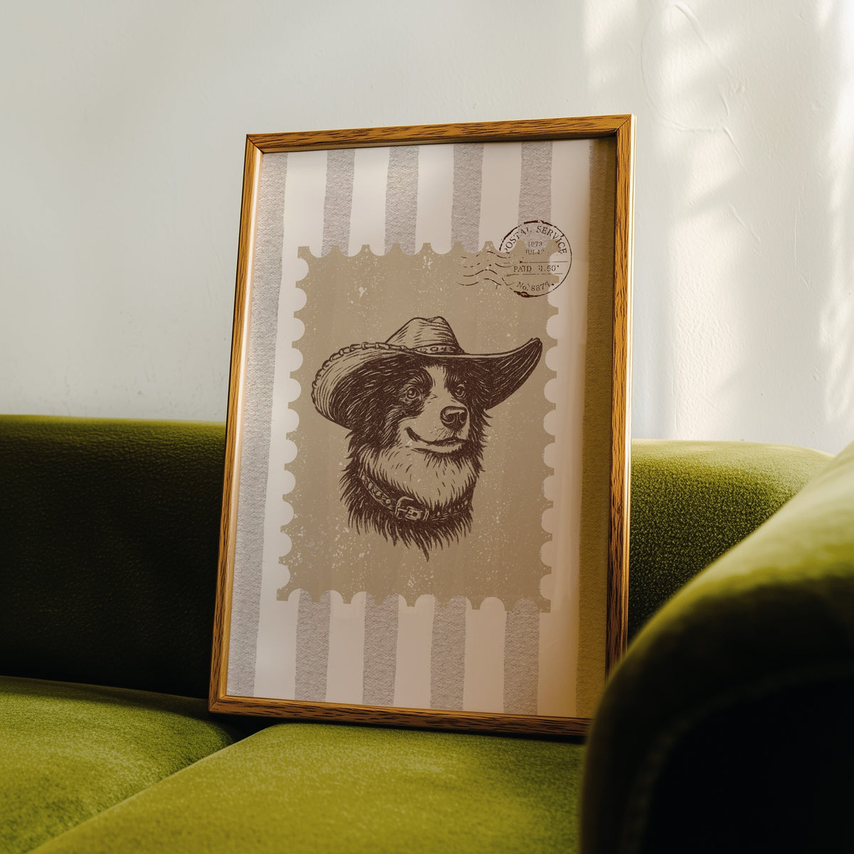 Collie cowboy hat stamp print in an oak frame leaning on a green velvet sofa