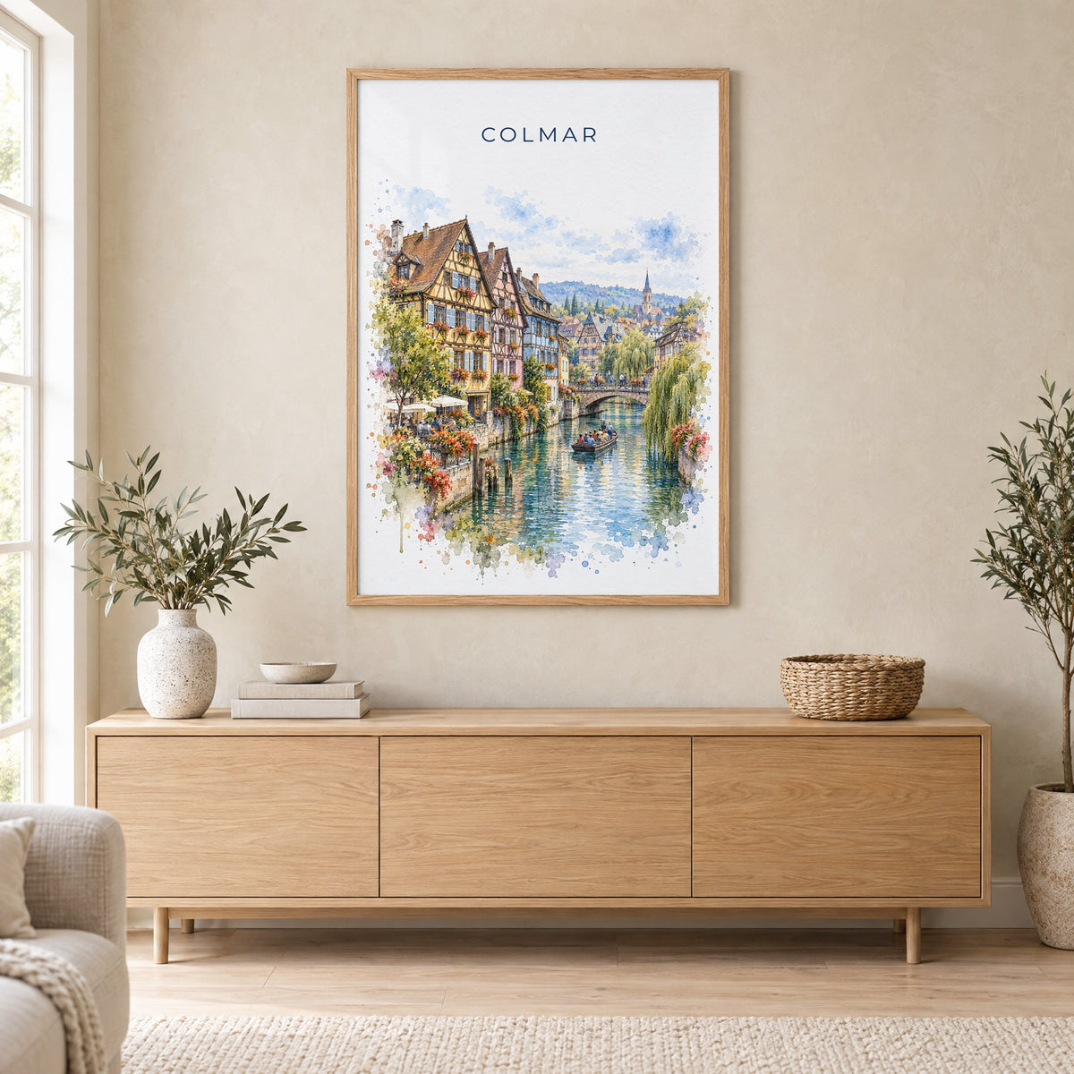 Colmar watercolor print in an oak frame above a light wood sideboard in a Scandinavian living room