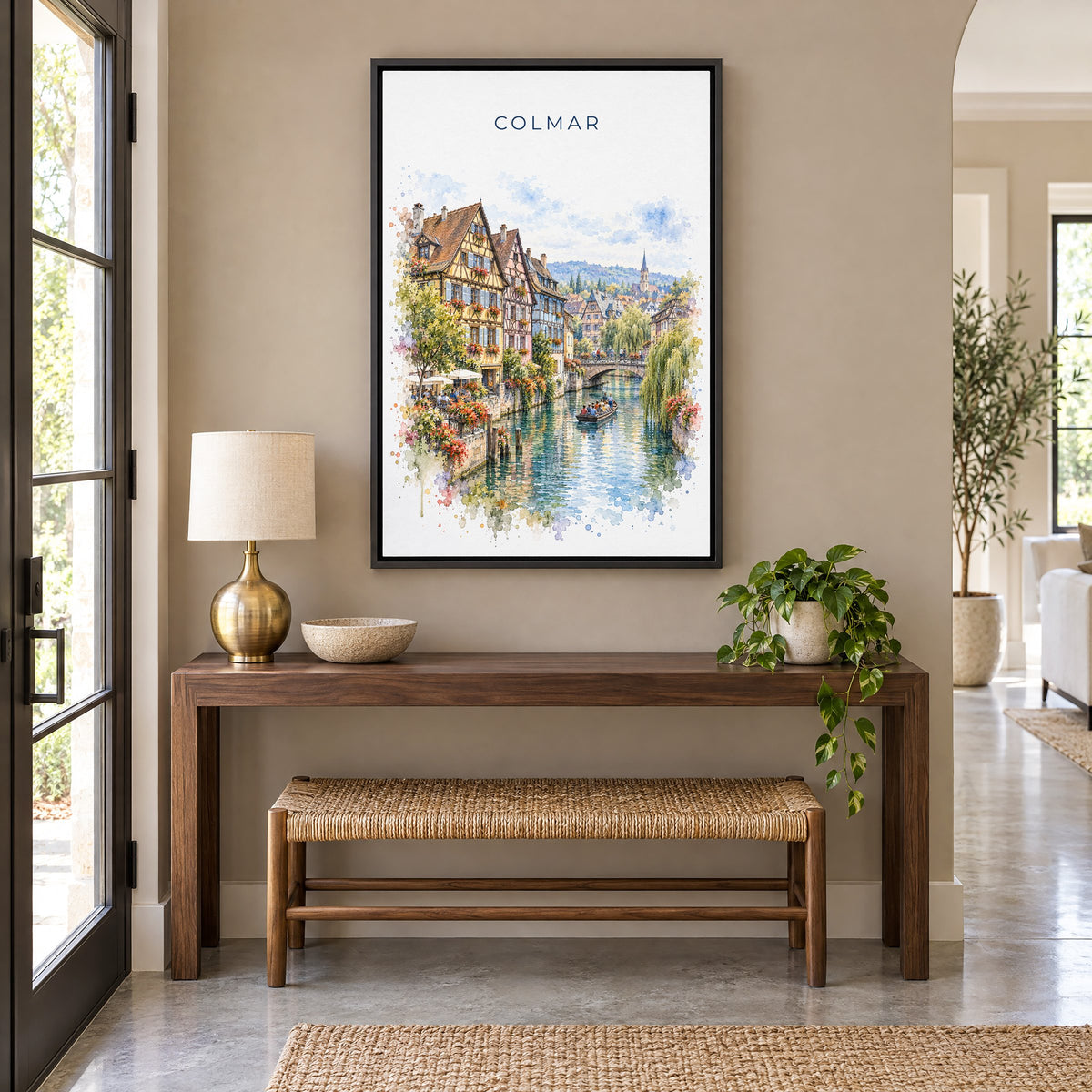 Colmar watercolor print as a black floater canvas above a walnut console and woven bench in an entryway