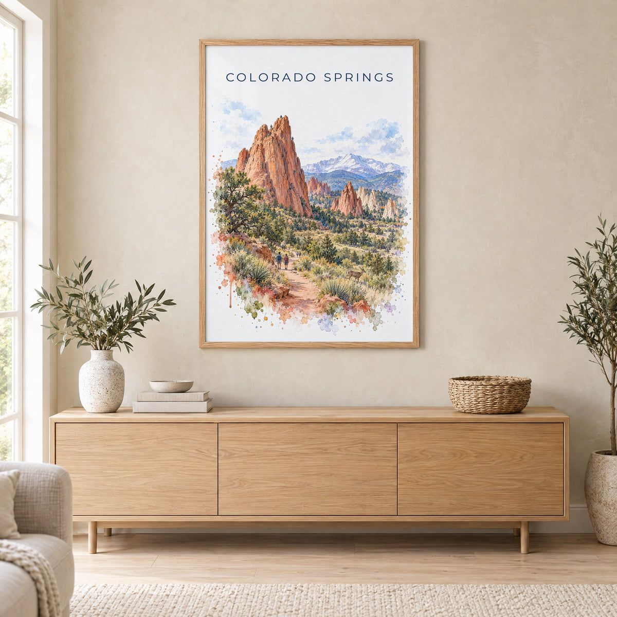 Colorado Springs watercolor print in an oak frame above a light wood sideboard in a Scandinavian living room