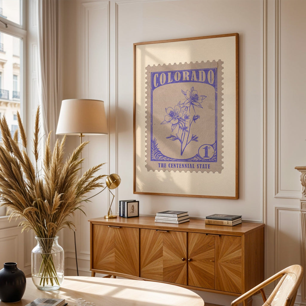 Colorado stamp print framed above a wooden sideboard, pampas grass in a glass vase and a floor lamp