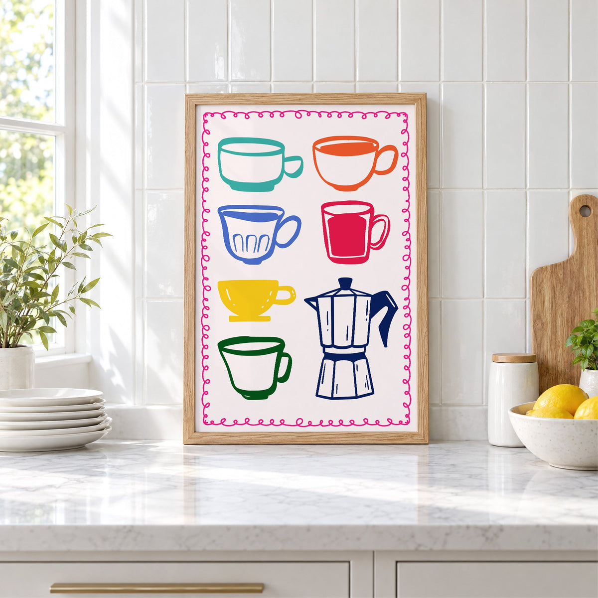 Colorful coffee cups and moka pot print in an oak frame leaning on a marble counter by white tiles and lemons