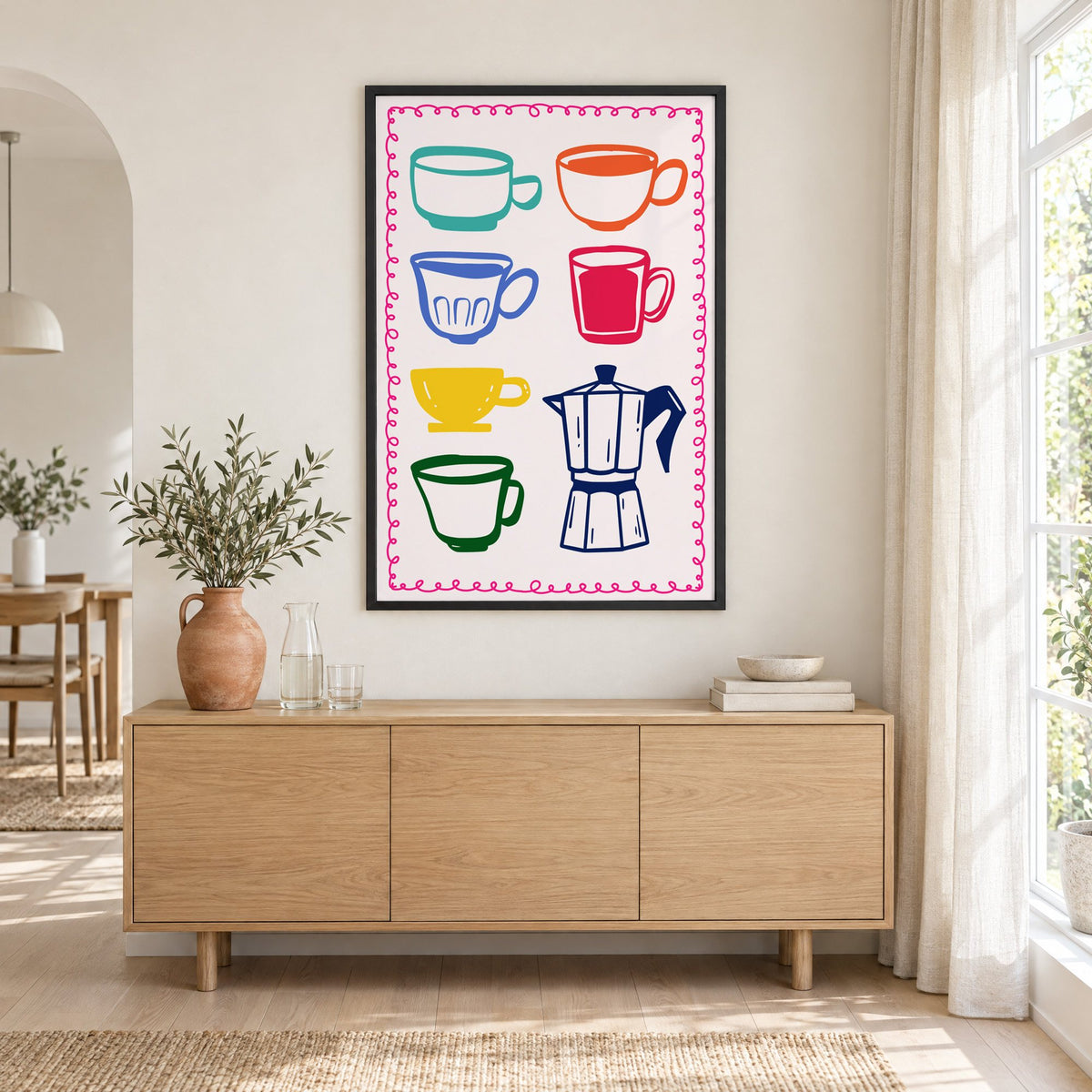 Colorful coffee cups and moka pot print in a black frame above an oak sideboard with a terracotta vase of olive branches