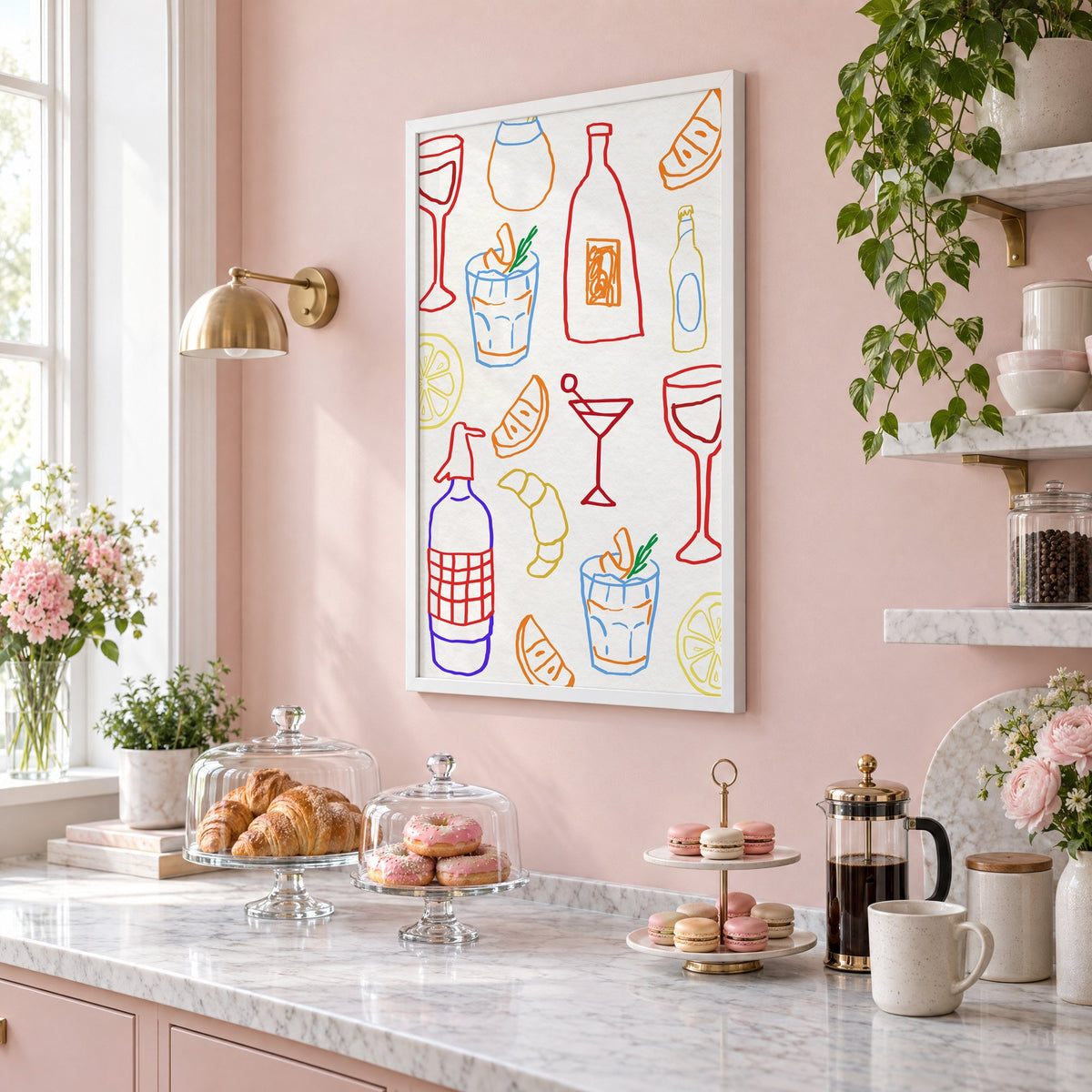 Colorful bar drinks doodle pattern print in a white frame on a blush pink wall above a patisserie counter with croissants and macarons, seen at an angle
