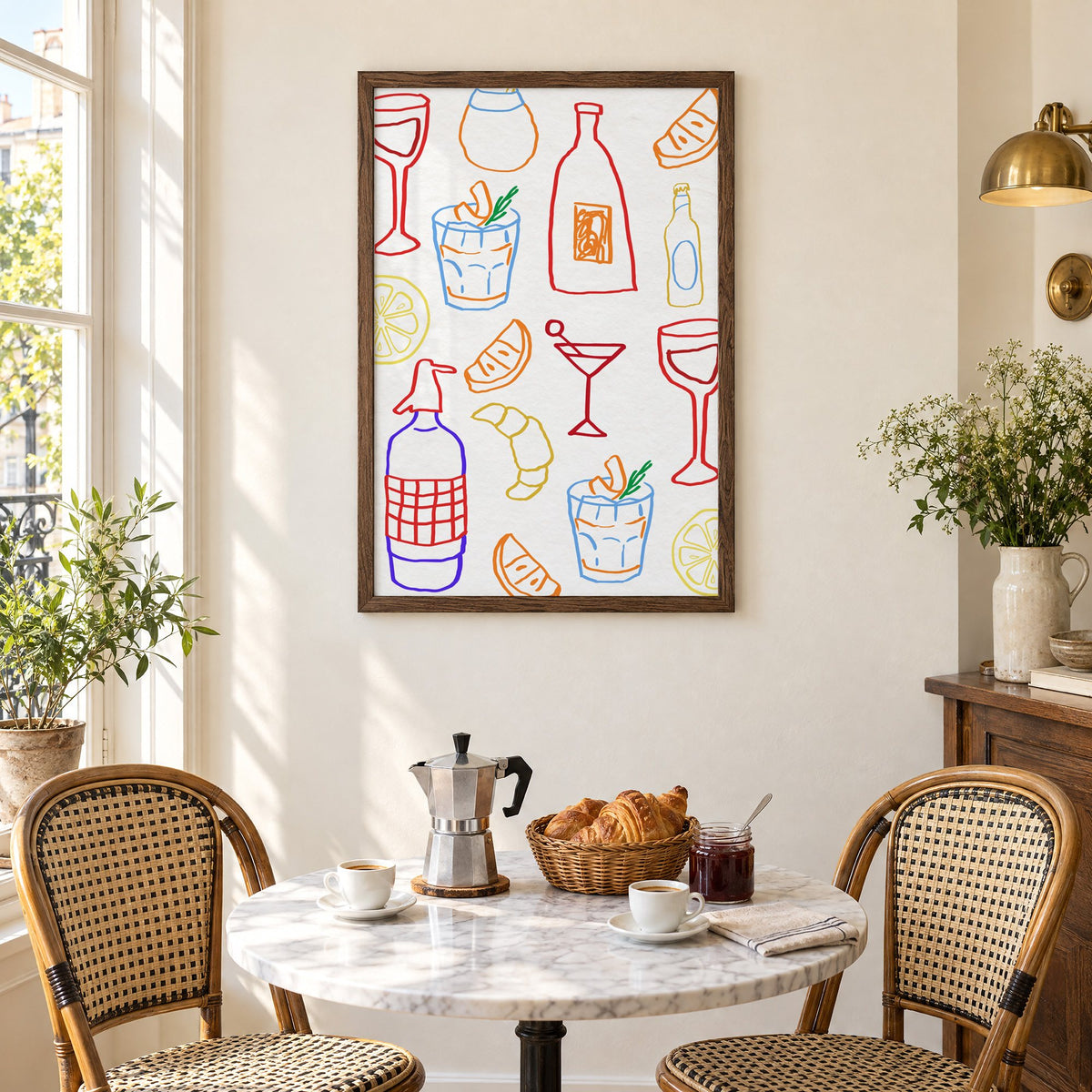Colorful bar drinks doodle pattern print in a walnut frame above a marble bistro table with croissants and rattan chairs