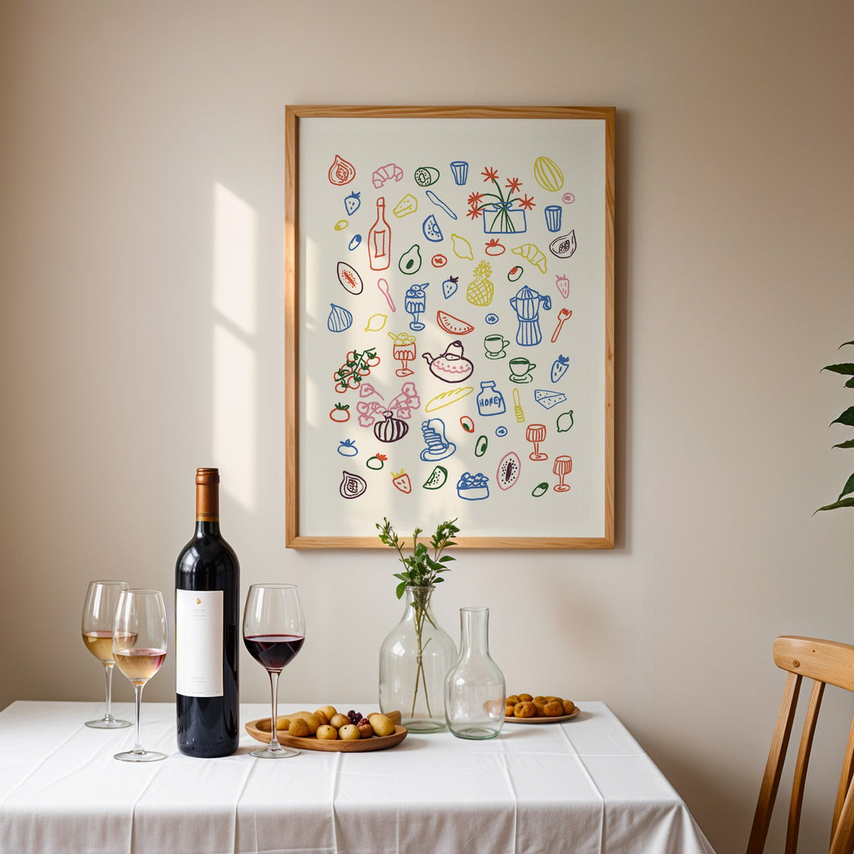 Colorful food doodle print in an oak frame above a table laid with red wine and glasses