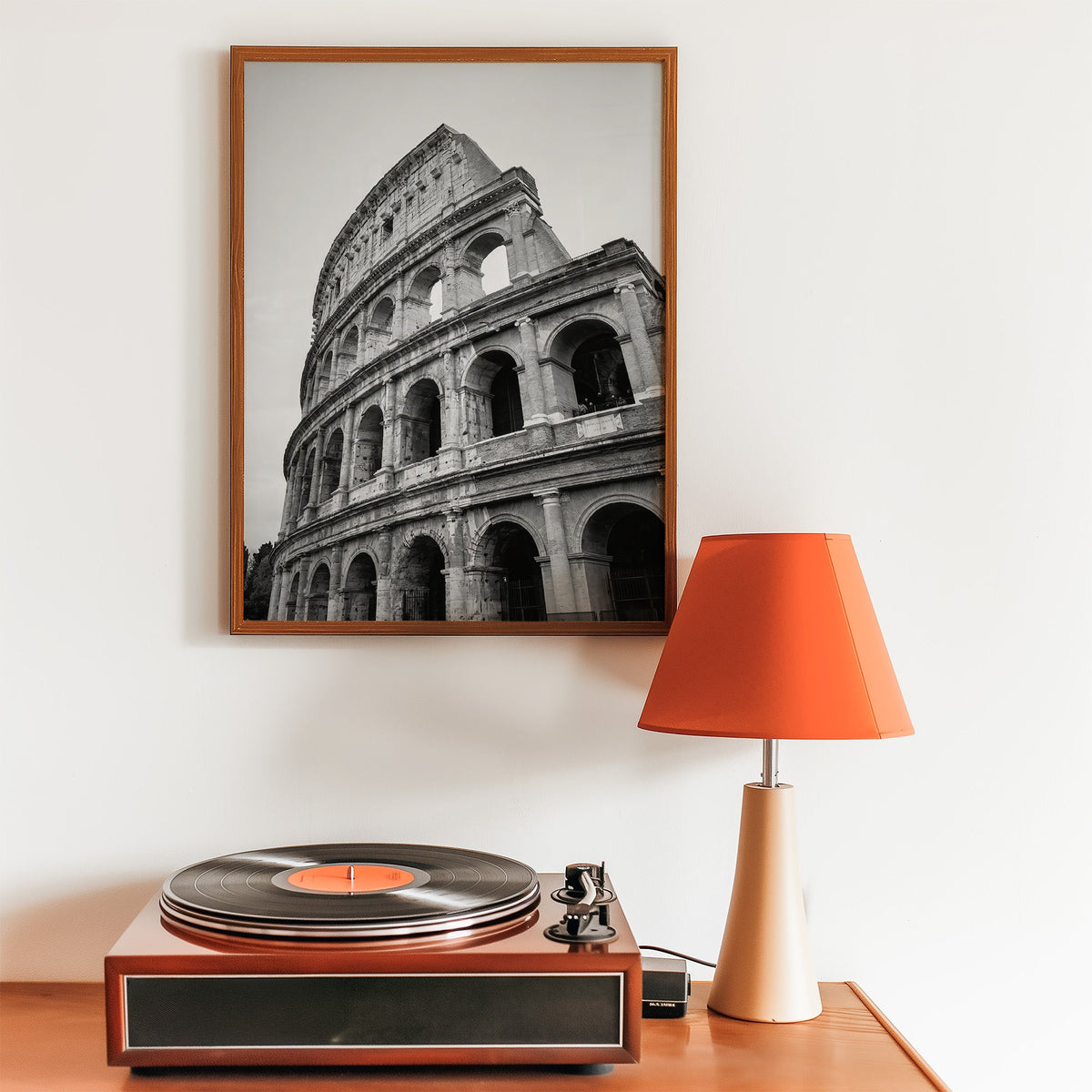 Colosseum Rome arches from below print in a walnut frame above a record player and orange lamp