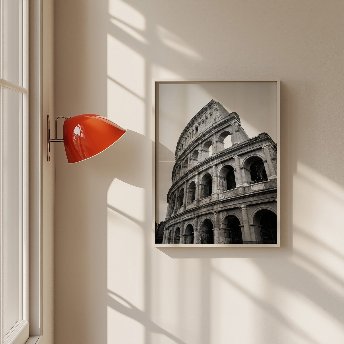 Colosseum Rome arches from below print in a white frame on a sunlit wall beside a red sconce