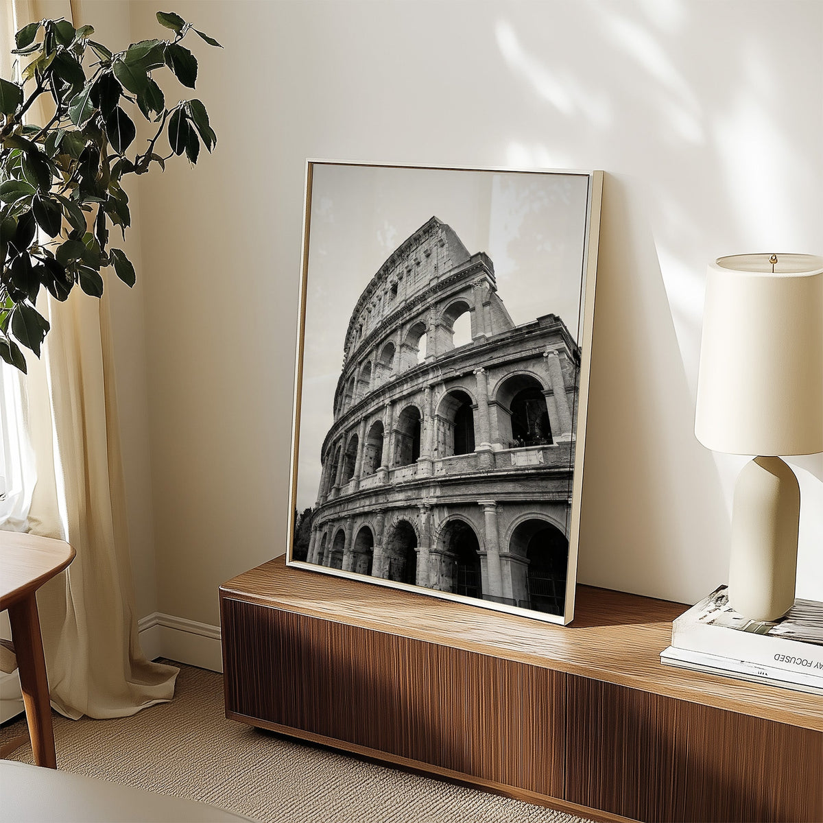 Colosseum Rome arches from below print in a white frame on a walnut sideboard beside a ceramic lamp