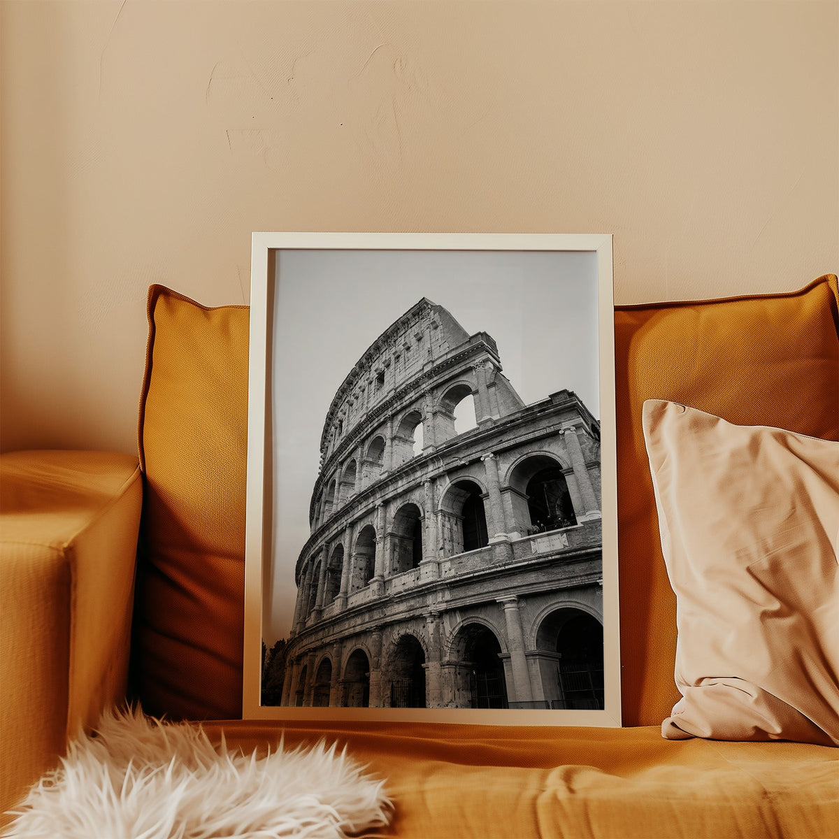 Colosseum Rome arches from below print in a white frame leaning on a mustard velvet sofa
