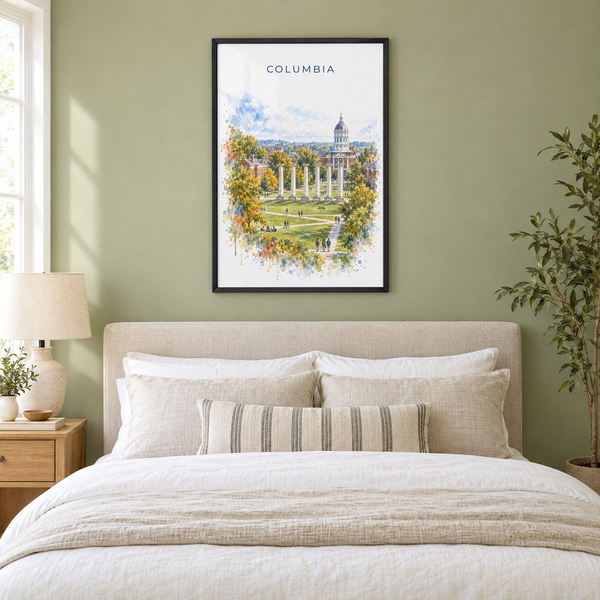 Columbia, Missouri watercolor print in a black frame above an upholstered headboard in a sage green bedroom