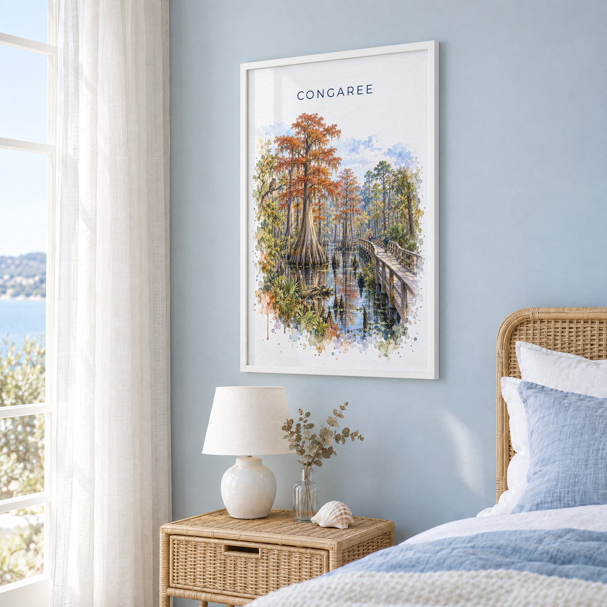 Congaree National Park watercolor print in a white frame on a pale blue wall beside a rattan bed in a coastal bedroom