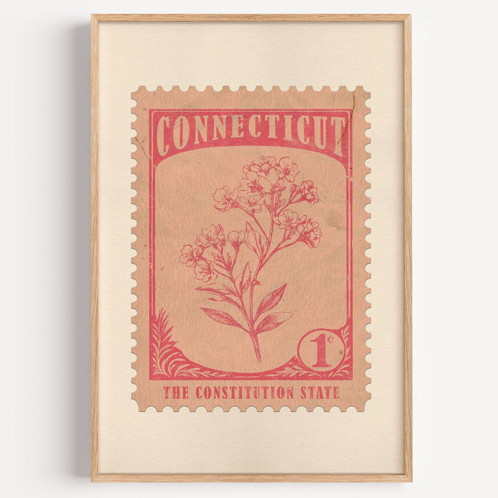 Connecticut state flower stamp print in coral red on blush, light oak frame on a plain white wall
