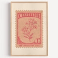 Connecticut state flower stamp print in coral red on blush, light oak frame on a plain white wall