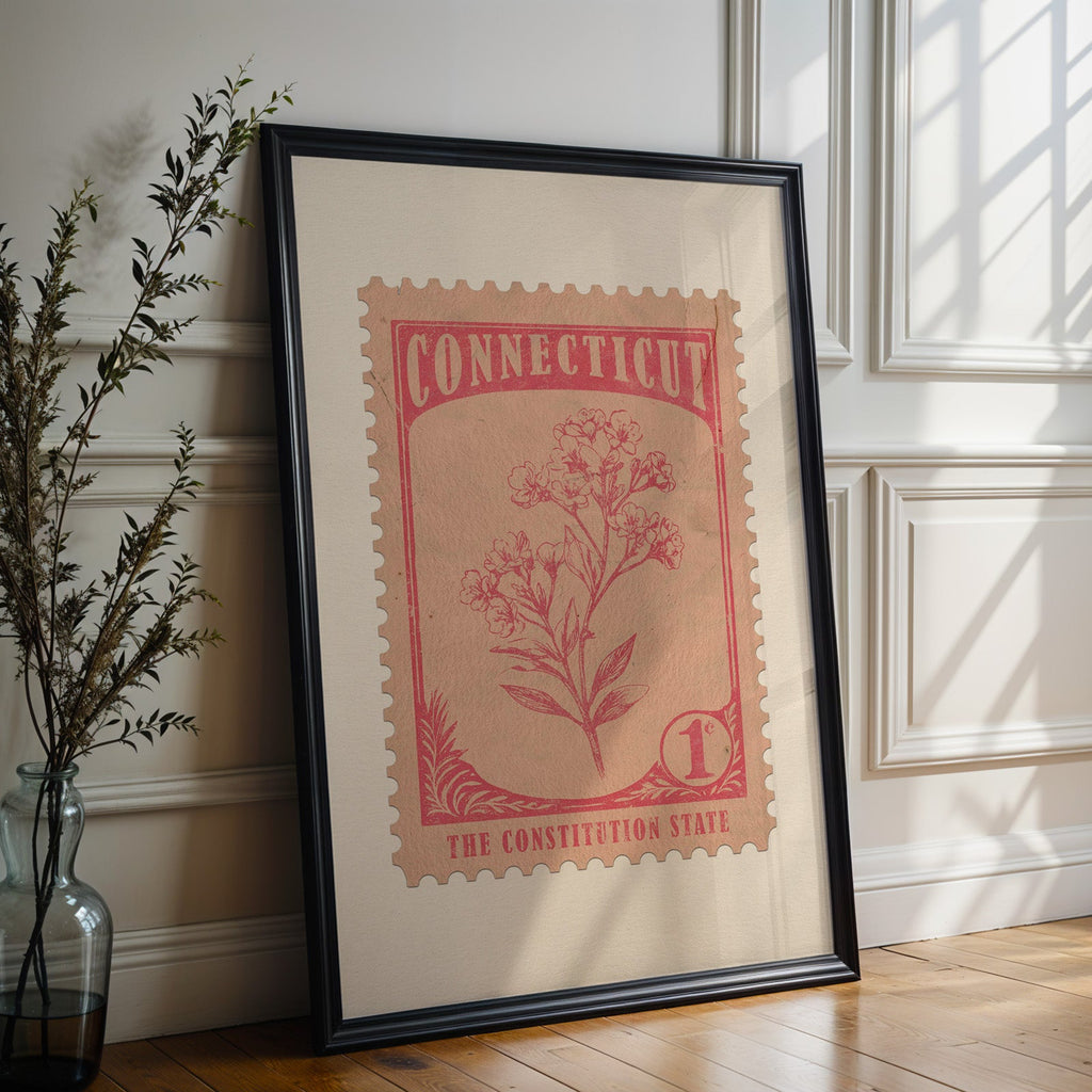Connecticut state flower print in a black frame leaning against a white panelled wall beside olive branches