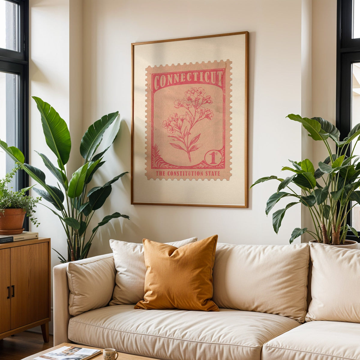 Connecticut state flower print framed above a cream sofa with an ochre cushion and large plants either side