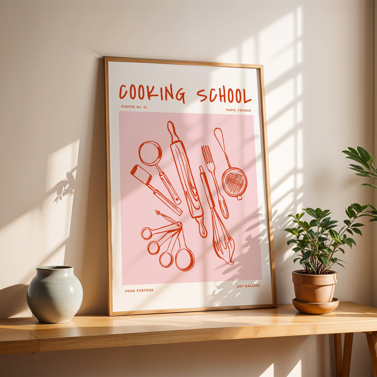 Cooking School utensils print in a slim oak frame on a console with a grey-blue vase