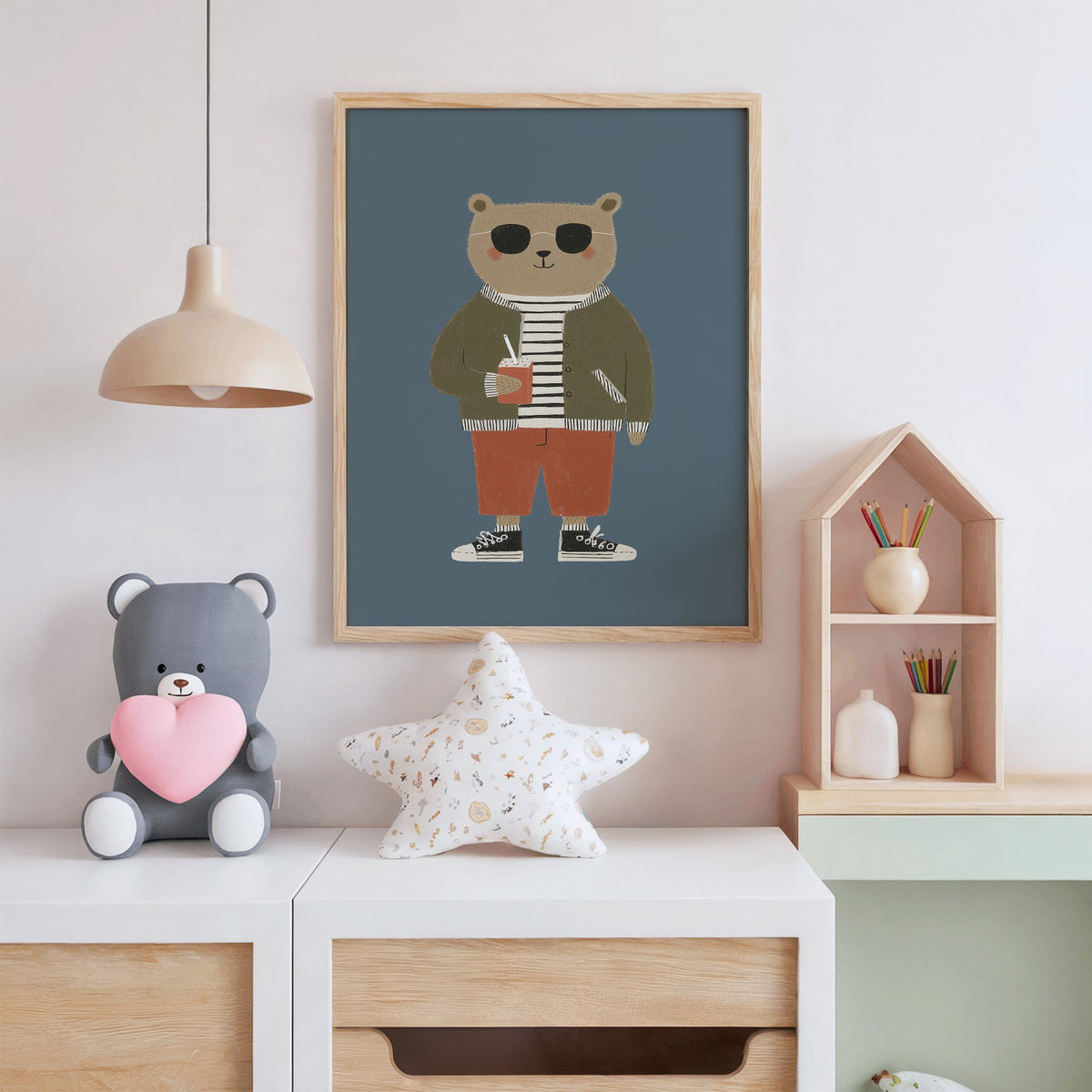 Cool bear sunglasses juice box nursery print in an oak frame above a white dresser with a star pillow and house shelf