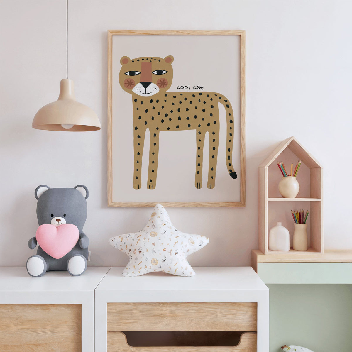 Cool cat cheetah nursery print in an oak frame above a white dresser with a star pillow and house shelf