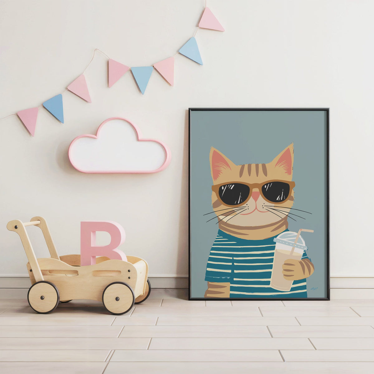 Orange tabby cat with iced drink nursery print in a black frame under pastel bunting by a wooden baby walker