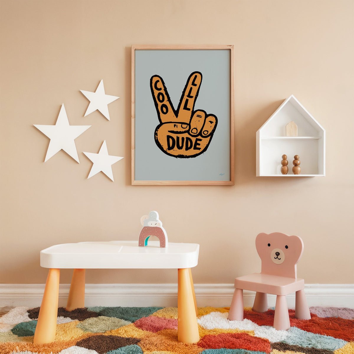 Cool dude peace sign hand nursery print in an oak frame on a peach wall above a kids table with wall stars