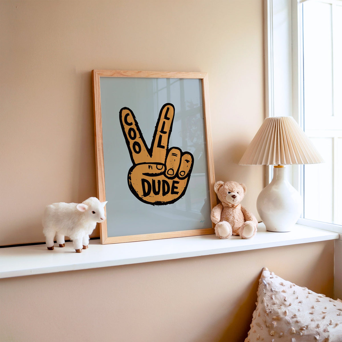 Cool dude peace sign hand nursery print in an oak frame on a window ledge with a toy lamb and teddy