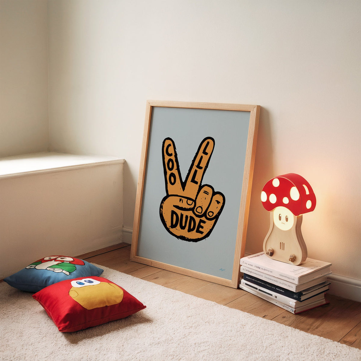 Cool dude peace sign hand nursery print in an oak frame leaning on a rug beside a mushroom lamp and floor cushions