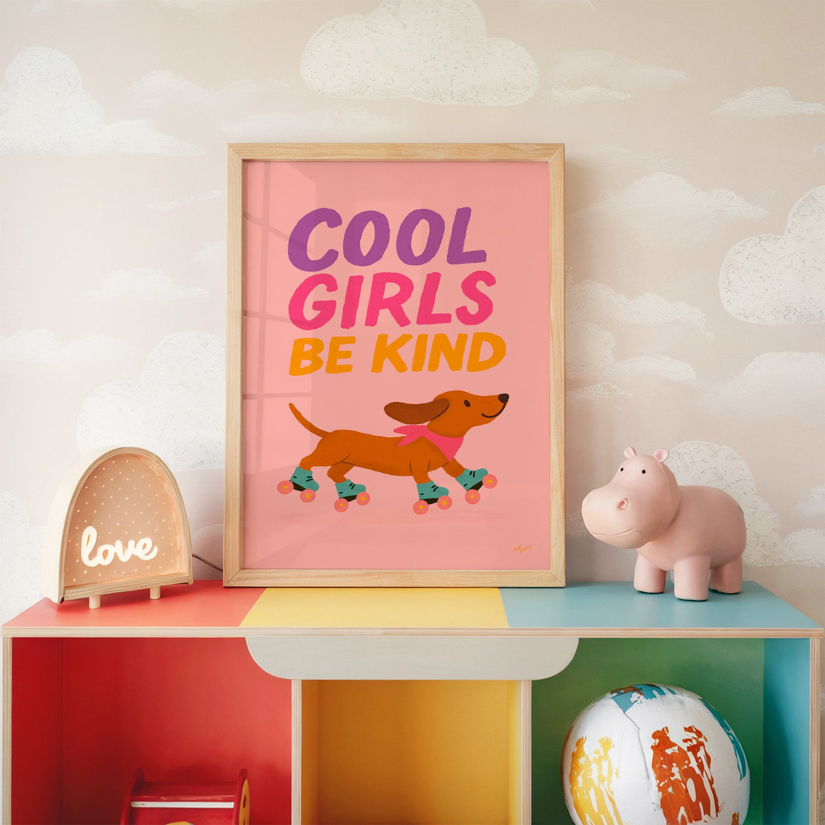 Cool girls be kind dachshund nursery print in an oak frame on a rainbow toy shelf against cloud wallpaper