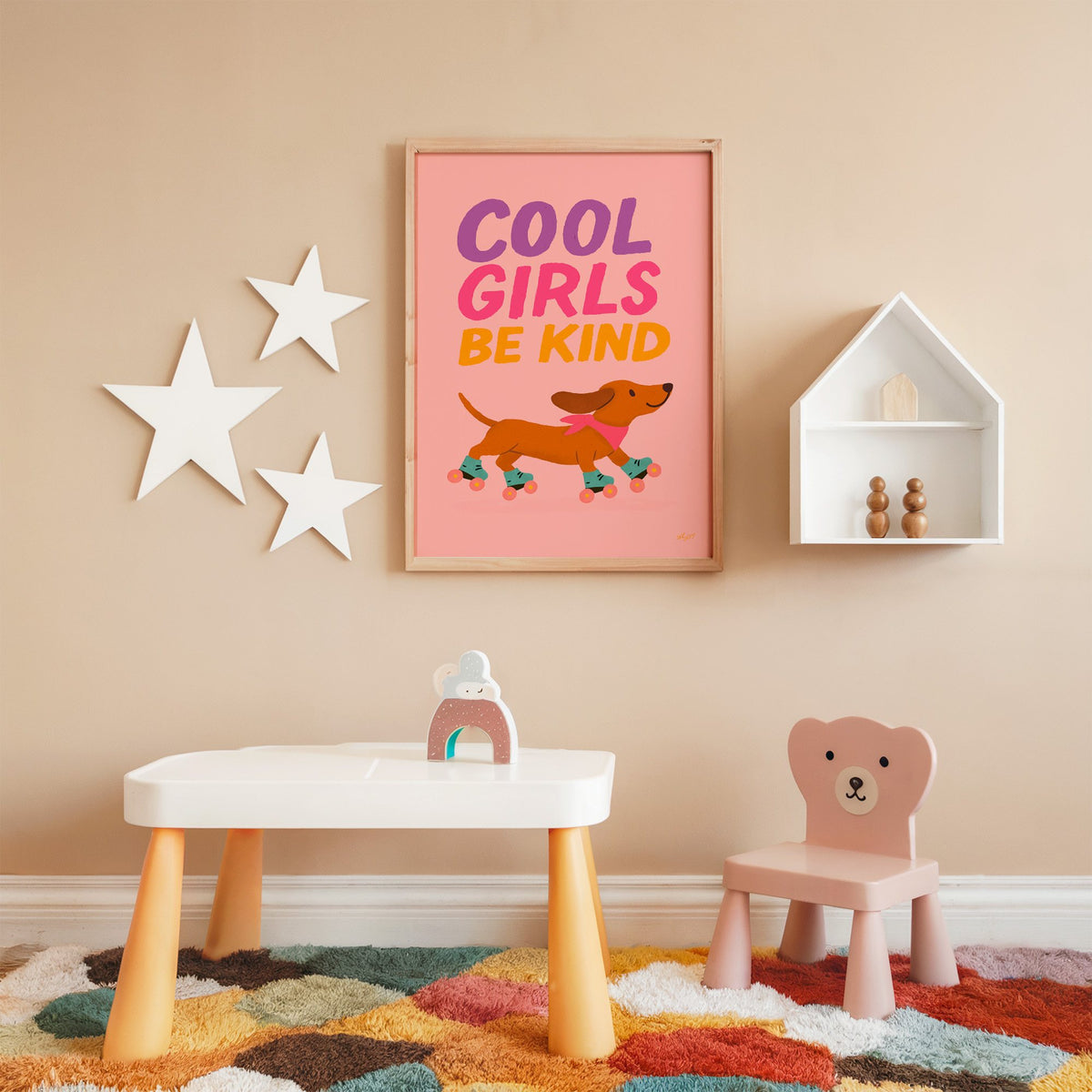 Cool girls be kind dachshund nursery print in an oak frame on a peach wall above a kids table with wall stars