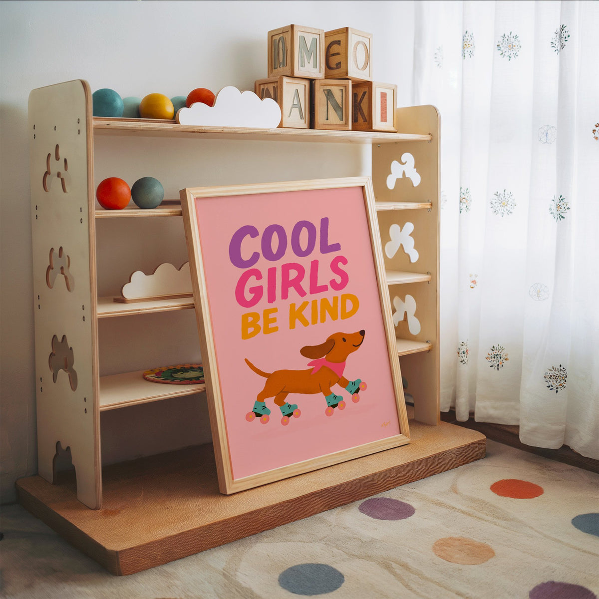 Cool girls be kind dachshund nursery print in an oak frame leaning on a toy shelf with wooden letter blocks