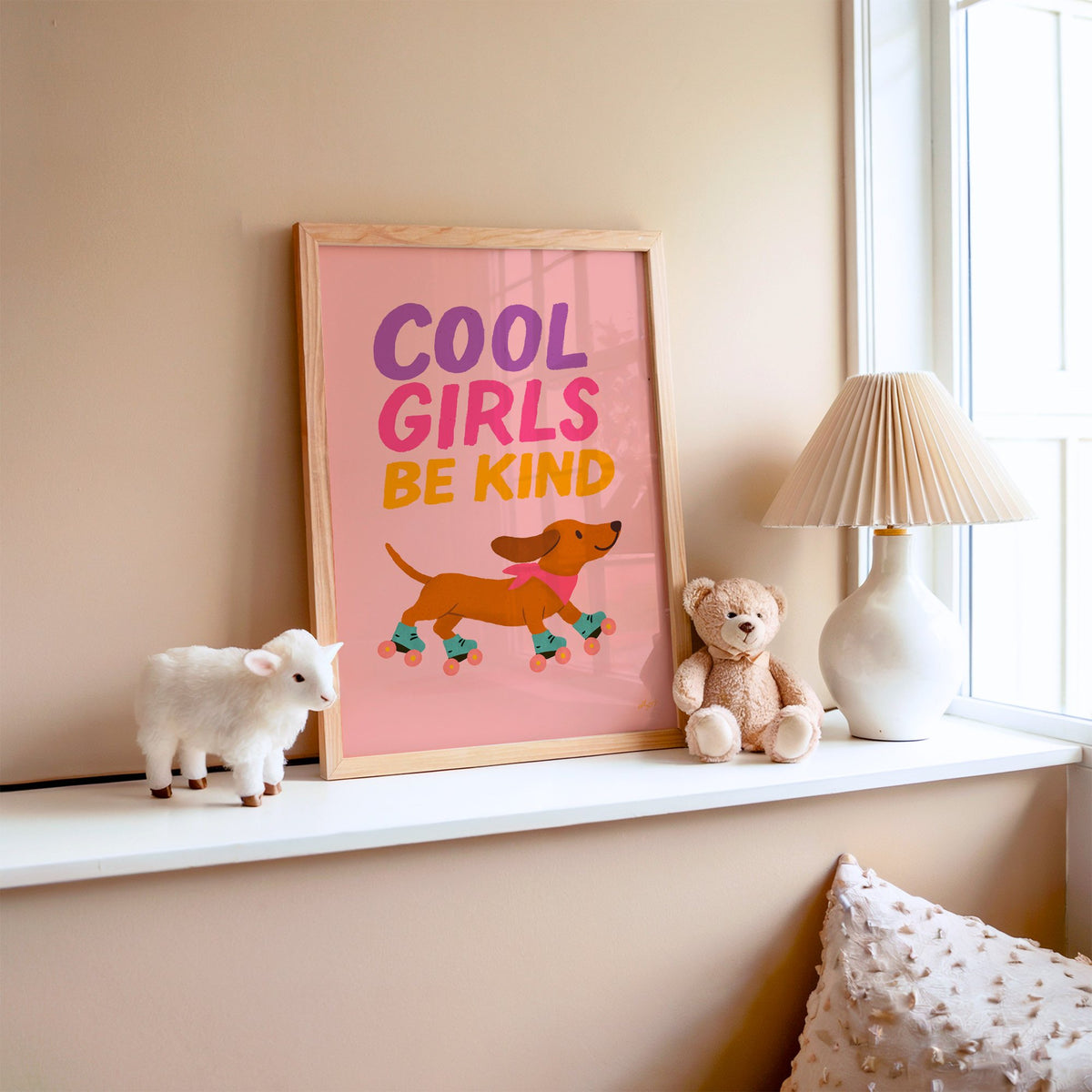 Cool girls be kind dachshund nursery print in an oak frame on a window ledge with a toy lamb and teddy