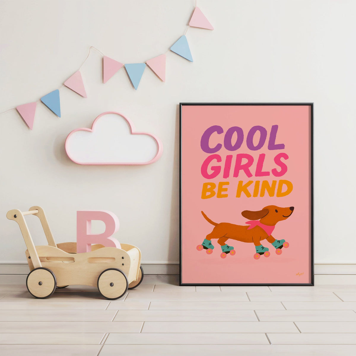 Cool girls be kind dachshund nursery print in a black frame under pastel bunting by a wooden baby walker