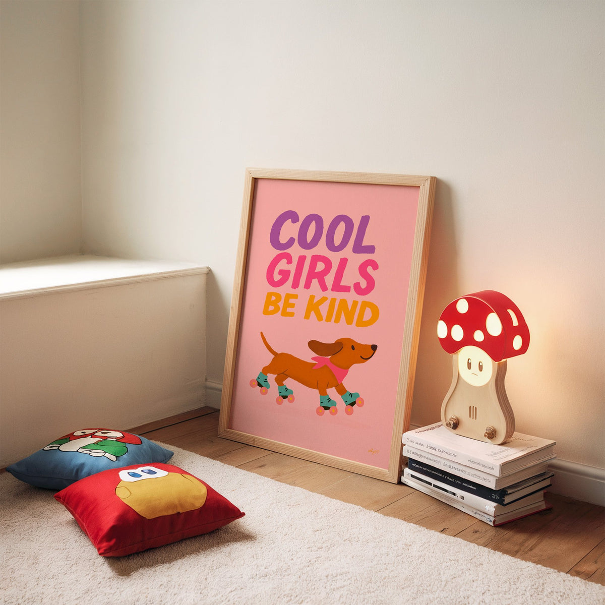 Cool girls be kind dachshund nursery print in an oak frame leaning on a rug beside a mushroom lamp and floor cushions