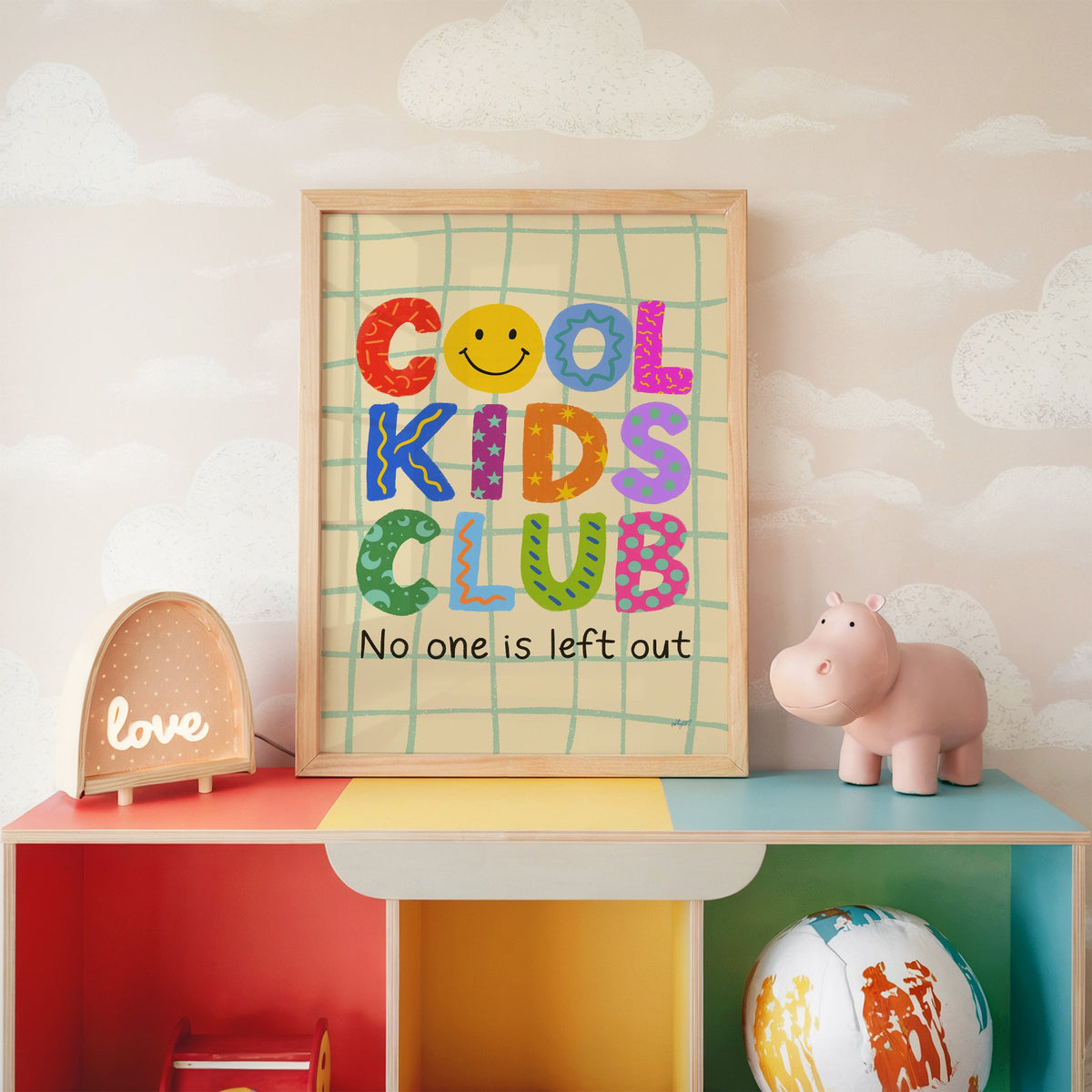 Cool kids club colourful letters nursery print in an oak frame on a rainbow toy shelf against cloud wallpaper