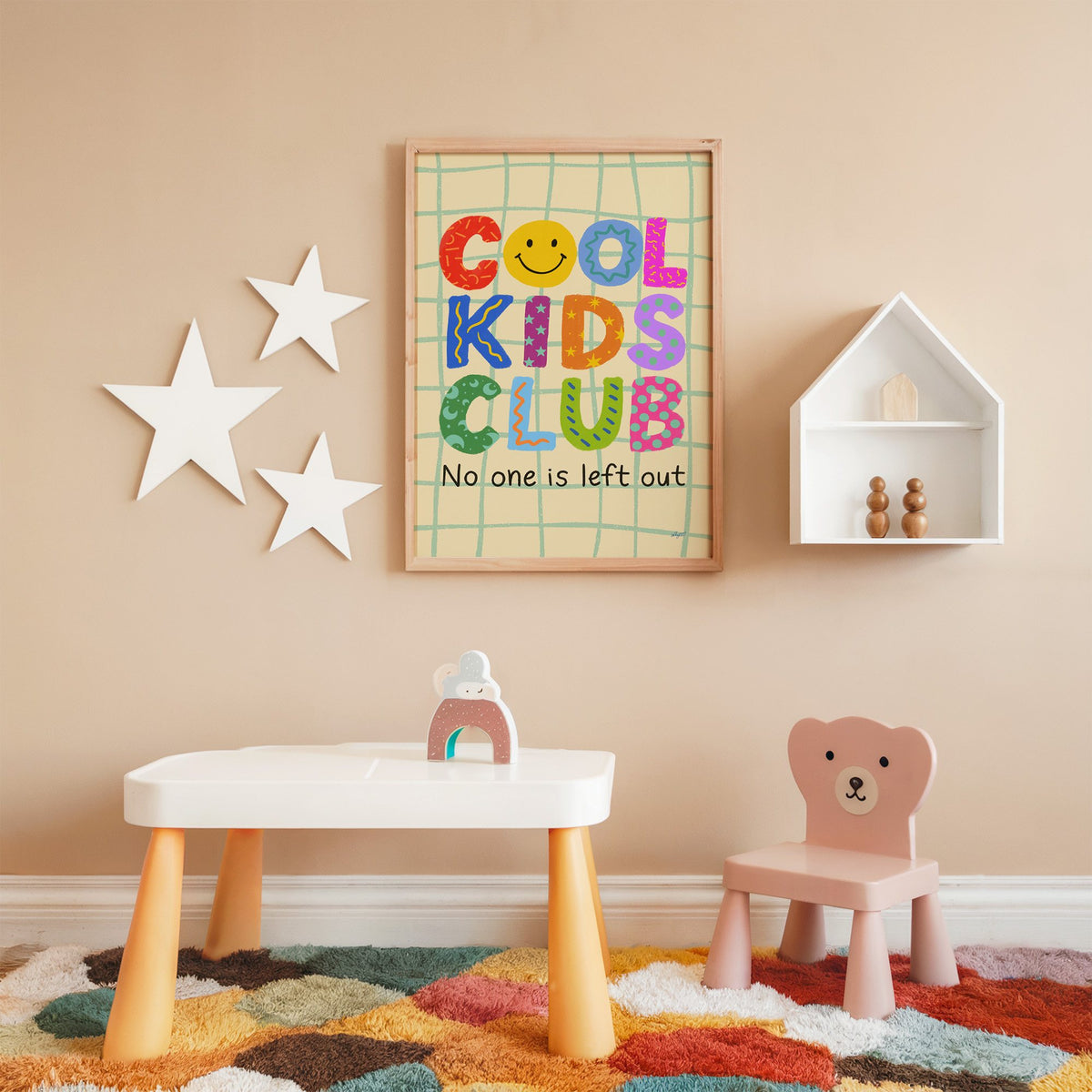 Cool kids club colourful letters nursery print in an oak frame on a peach wall above a kids table with wall stars