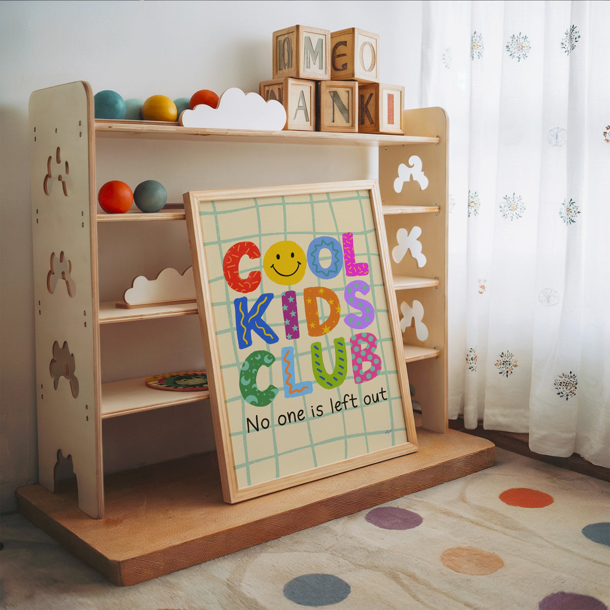 Cool kids club colourful letters nursery print in an oak frame leaning on a toy shelf with wooden letter blocks