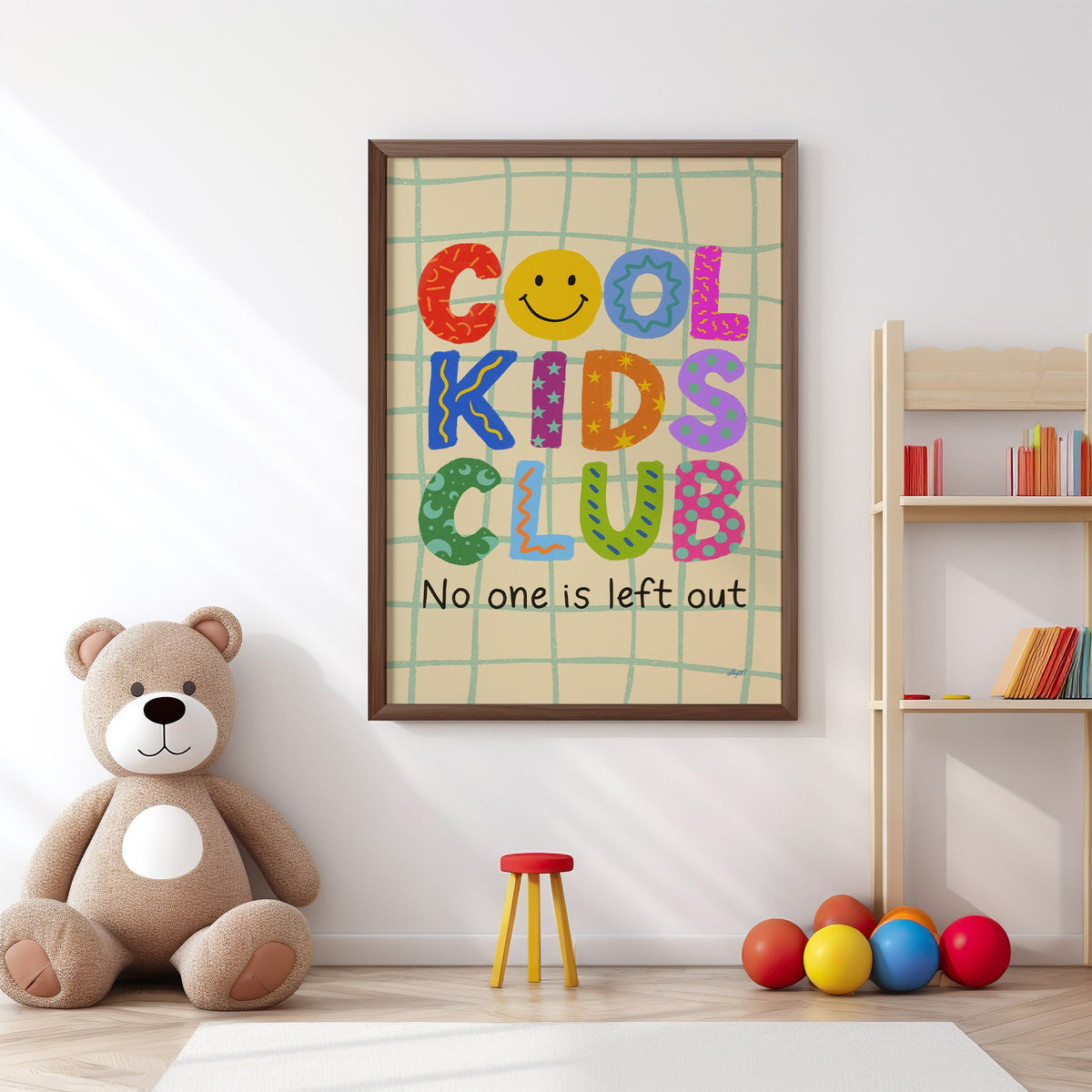 Cool kids club colourful letters nursery print in a walnut frame above a big teddy bear by a bookshelf