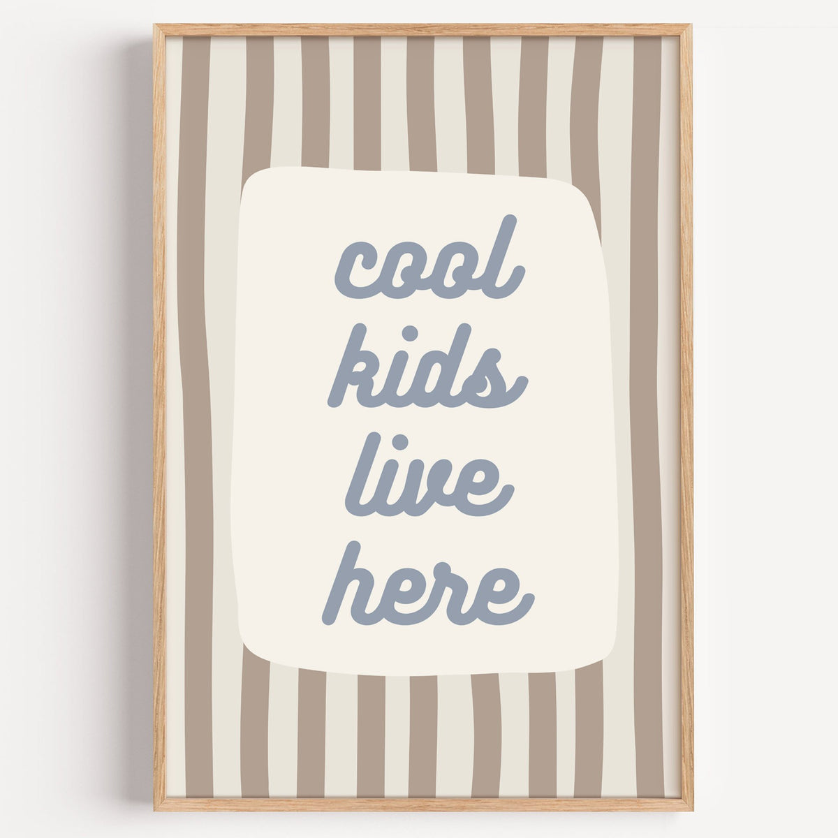 Cool kids live here nursery print in a light oak frame on a plain white wall