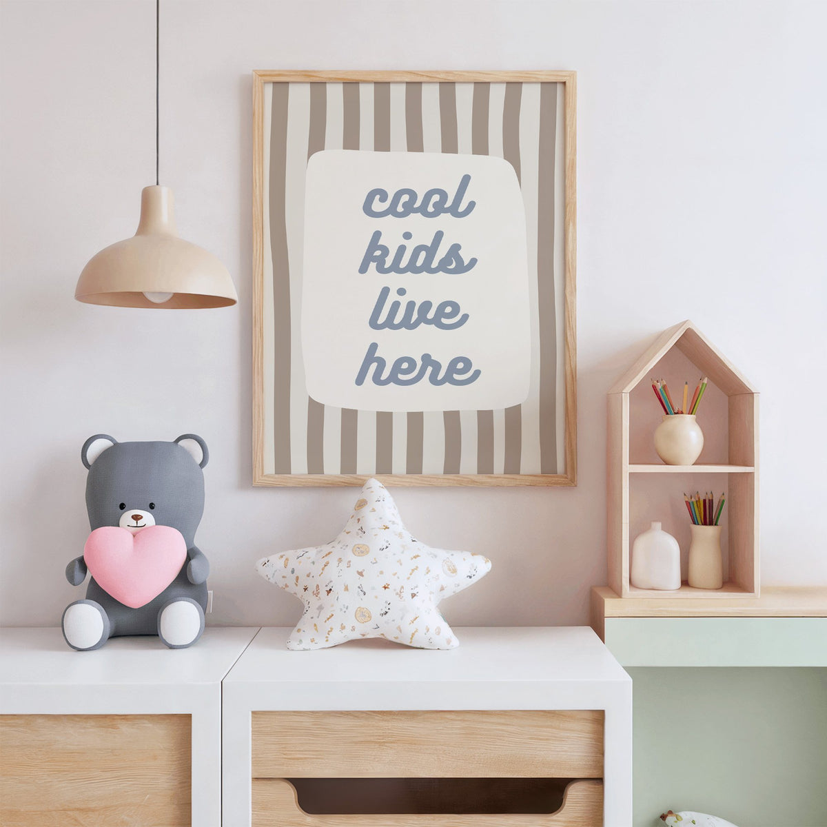 Cool kids live here nursery print in an oak frame above a white dresser with a star pillow and house shelf